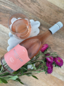 Highclare Estate Rosé wine bottle with glass and pink flowers.