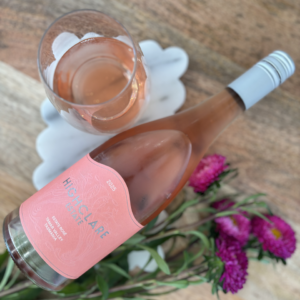 Highclare Estate Rosé wine bottle with glass and pink flowers.